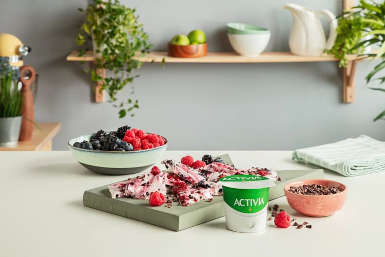 A tub of Activia low-calorie yogurt in front of chocolate bits and fruit