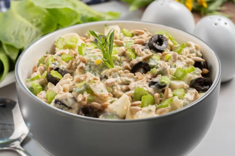 A bowl of chicken salad topped with olives.