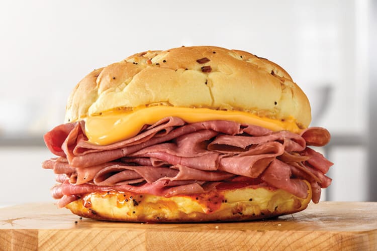 An Arby's Classic Beef ‘N Cheddar on a wooden board