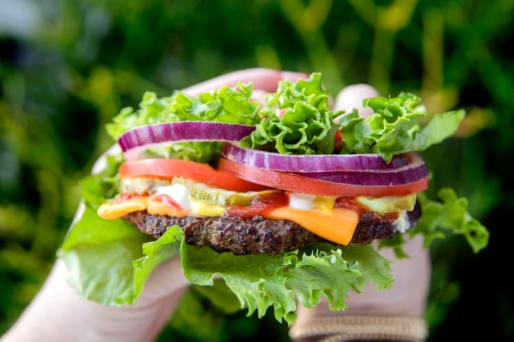 Hands holding a lettuce wrap burger from Carl's Jr.