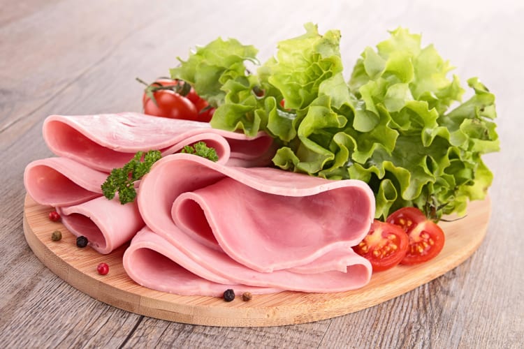 Ham slices, tomatoes and lettuce on a wooden serving board