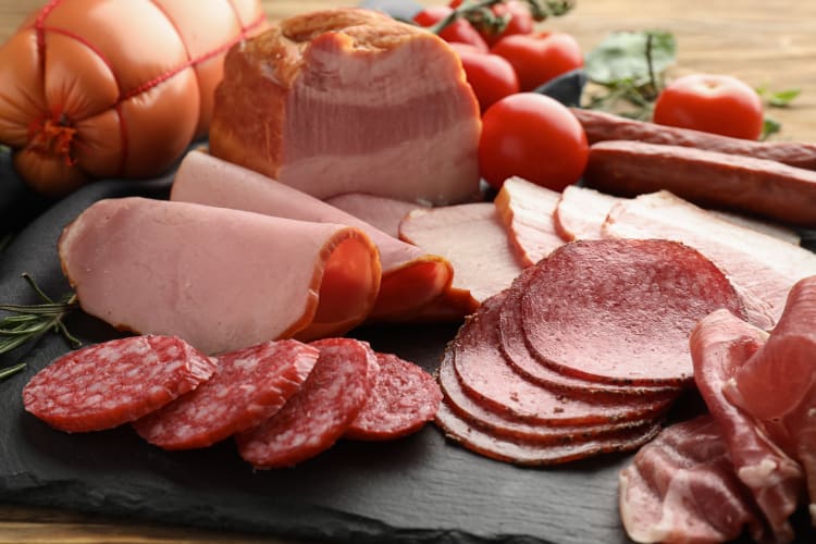 An assortment of deli meats on a black slate serving board