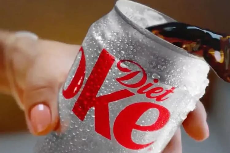 A hand throwing a can of diet coke.