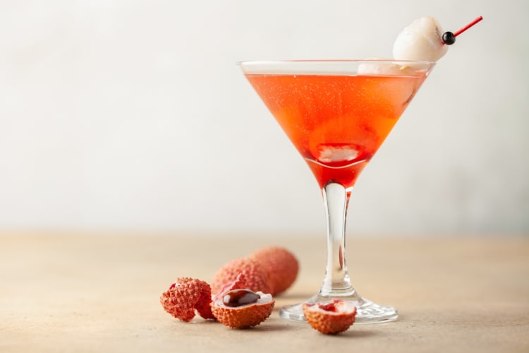 A lychee martini next to lychee fruit