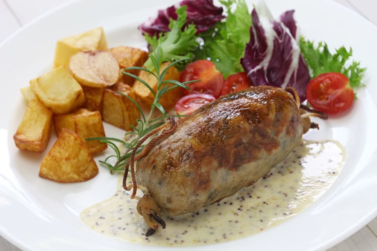 French sausage, potatoes and salad on a white plate