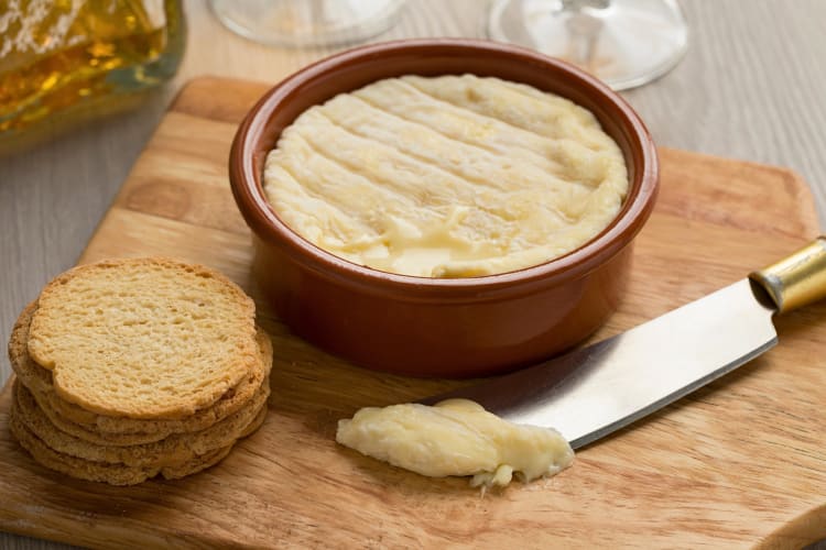 Saint-Marcellin, a delicious Lyon food, in a brown bowl next to crackers