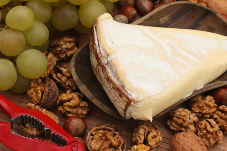 Vacherin, a delicious Lyon food, surrounded by grapes and walnuts