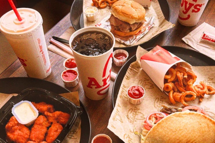 A table full of Arby's fast food and drinks.