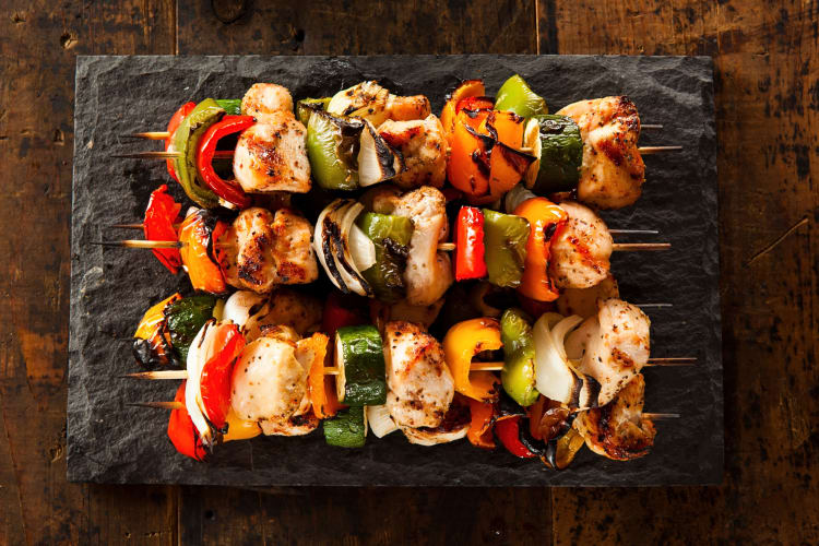 Three shish kebabs on a stone serving board