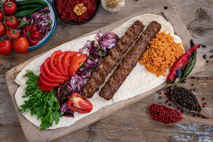 Adana Kebab and other foods on a wooden board