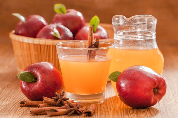 Apple cider vinegar served in a cup paired with apples and cinnamon
