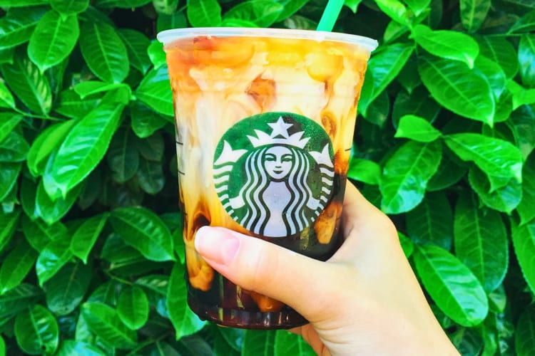 A hand holding a Starbucks Vanilla Sweet Cream Nitro Cold Brew