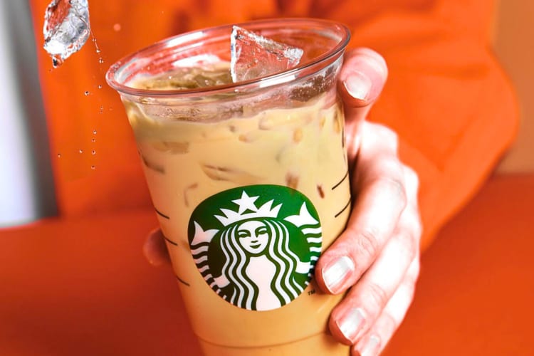 A hand holding an iced coffee, one of the most caffeinated drinks at Starbucks
