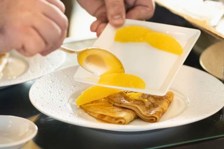 A chef putting mandarin on pancakes.