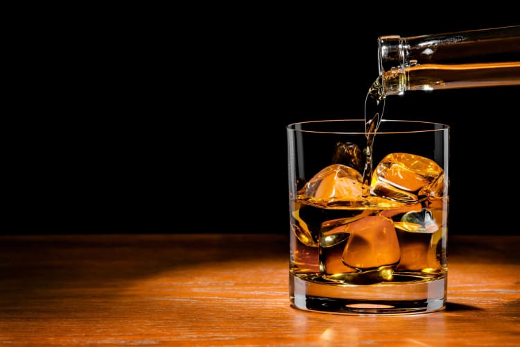 Pouring whiskey on a glass with ice