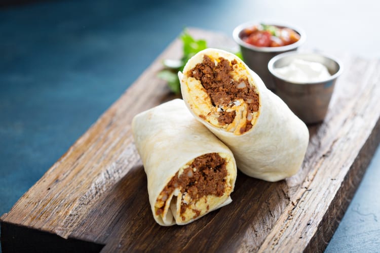 Chili cheese burrito served on a wooden board