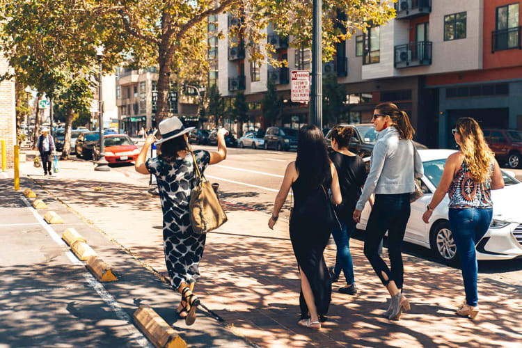 Four people on a food tour with a guide directing them around a city