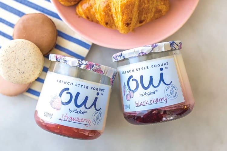 A jar of strawberry Oui yogurt next to a jar of blackberry Oui yogurt