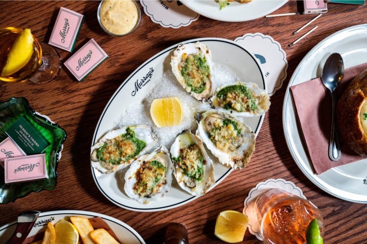 Oysters Rockefeller on a table with sides and plates