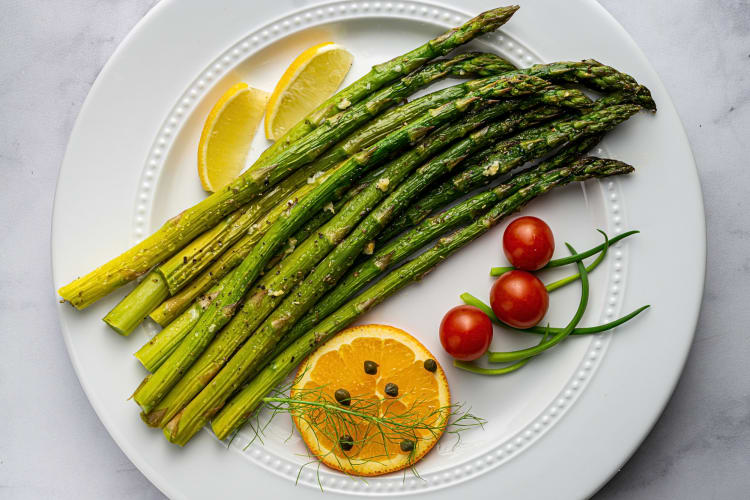 Aerial view of roasted asparagus, a popular Passover food, with tomatoes and lemon slices