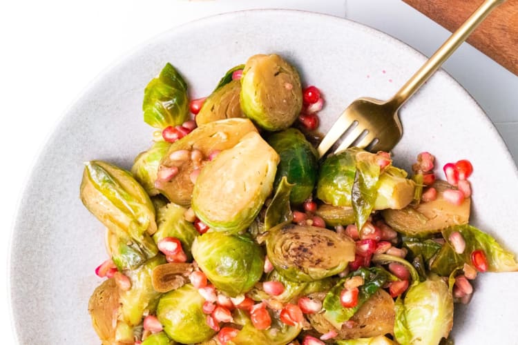 Half a plate full of Brussels sprouts, with a fork wedged in between