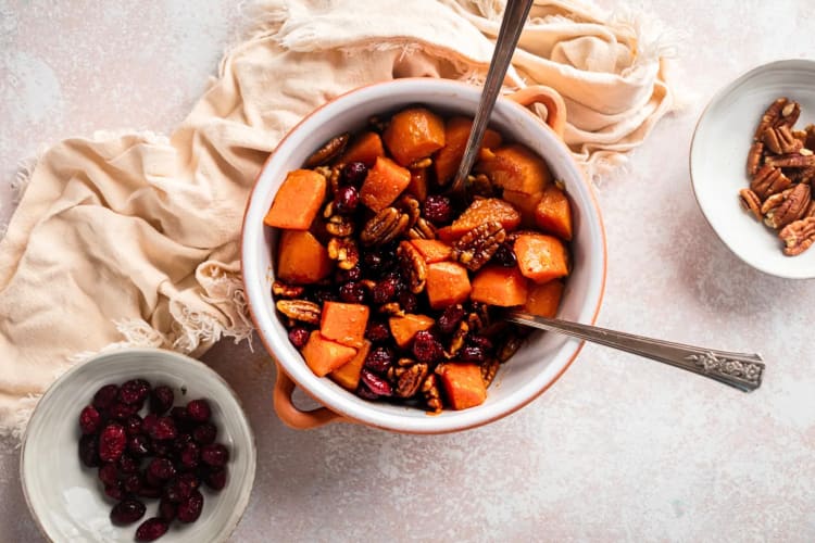Aerial view of a bowl of candied sweet potatoes in between dried cranberries and walnuts