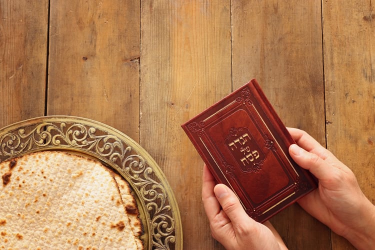 Aerial view of hands holding a Haggadah