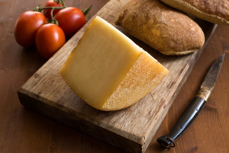 A sliced chunk of pecorino with bread and tomatoes 