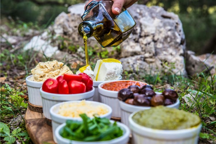 person pouring olive oil onto food