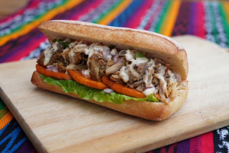 A ciabatta filled with chicharrón, salad and sauce