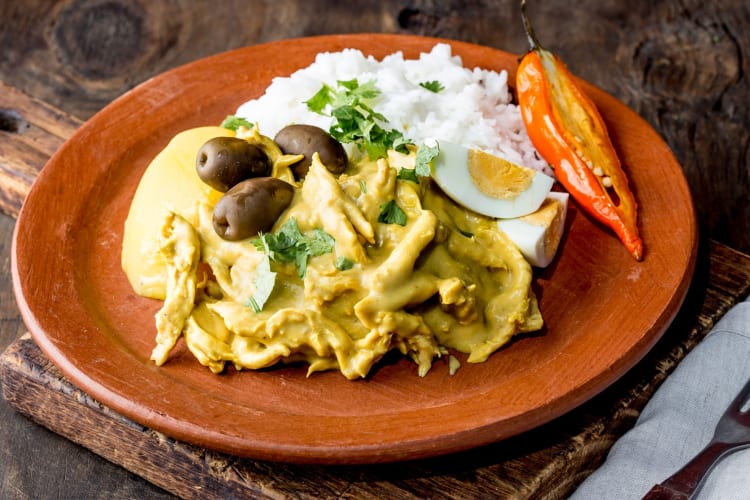 Aji de gallina with olives, egg and rice on clay plate