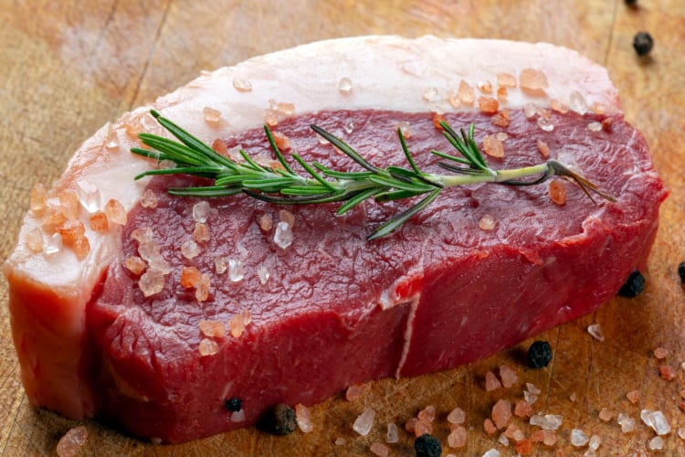 Sliced raw picanha topped with salt and rosemary