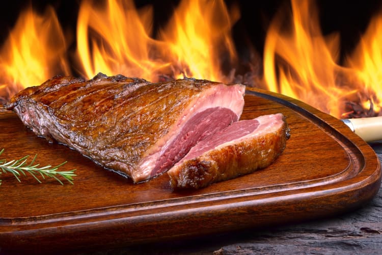 Picanha and rosemary on a wooden table in front of an oven