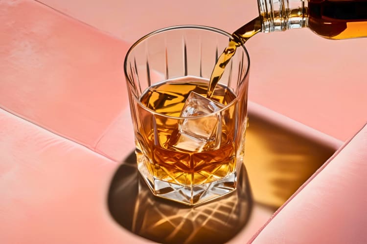 pouring a glass of neat whiskey on the rocks