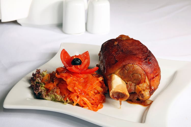 Koleno, a delicious Prague food, served on a white plate with vegetables