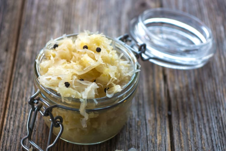 Sauerkraut in a glass jar on a wooden table.