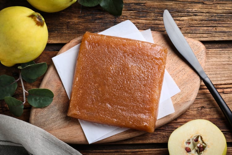 Quince paste on a wooden board next to whole quince fruits