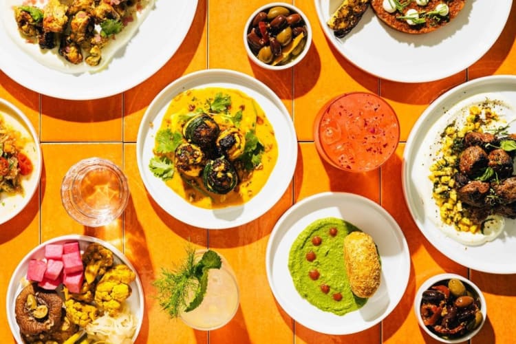 Plates of food, including cauliflower and a green dip with bread.