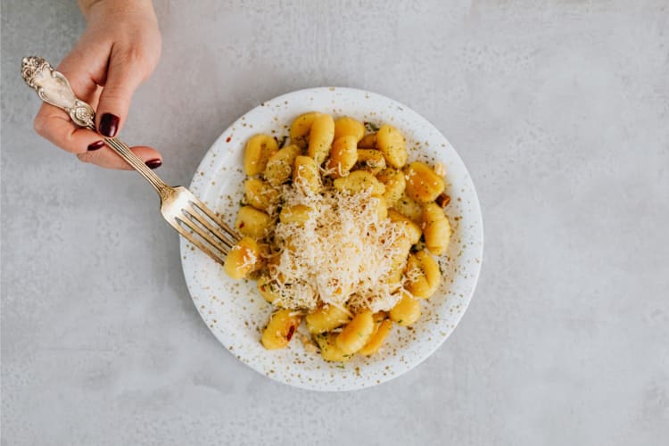 A person holding a fork while getting gnocchi