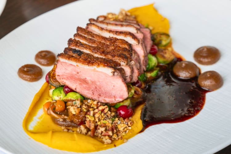 Crispy duck confit served over nuts and sauces