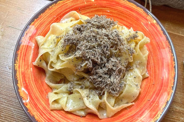 dish of pasta with shredded truffles in a red bowl