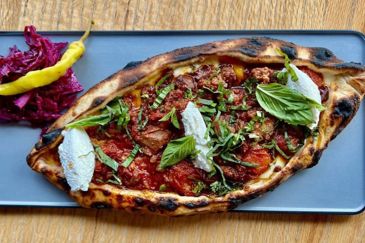 Wood-fired flatbread served on a plate on a wooden table