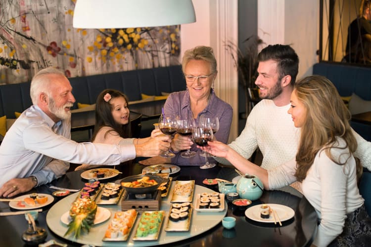 A family of five clinking glasses while eating at a sushi restaurant