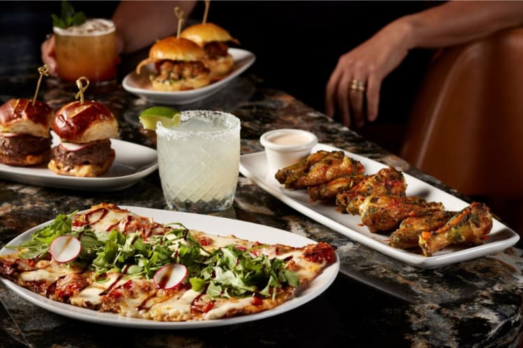 A table of food, including flatbread pizza and chicken wings