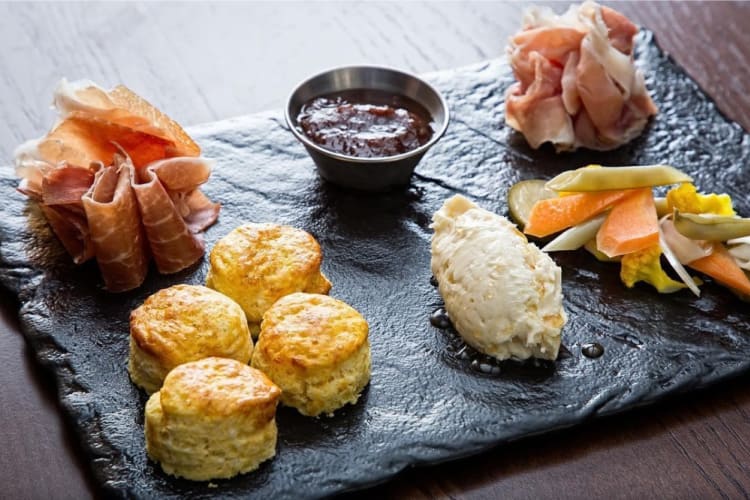 Biscuits, Parma ham and condiments on a slate serving board