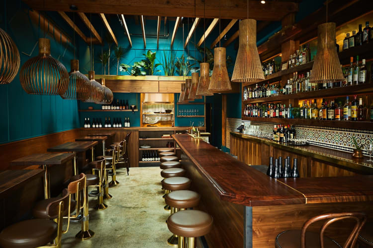 luxurious interior of an Indian restaurant with teal walls and wooden bar