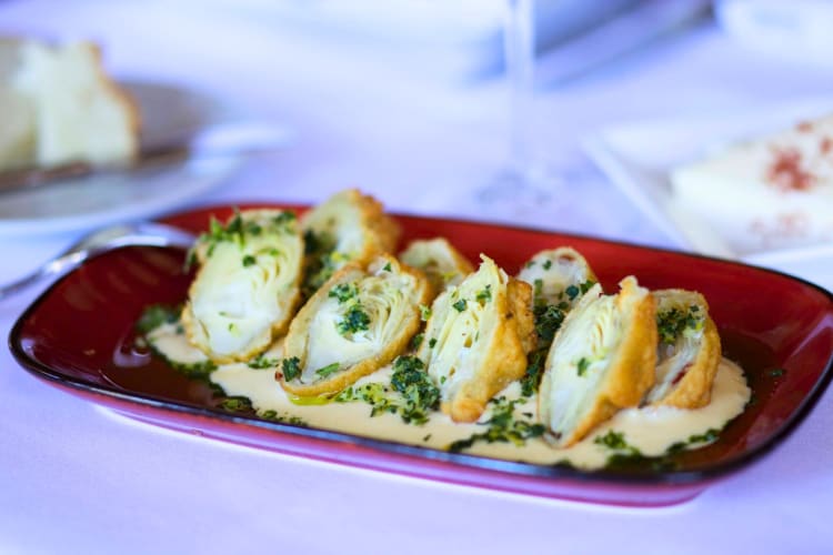 Crusted baby artichokes, preserved in sweet lemon aioli on a red plate