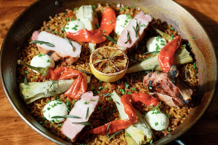 Paella with pork chop, artichoke hearts, rosemary aioli, and topped with peppers