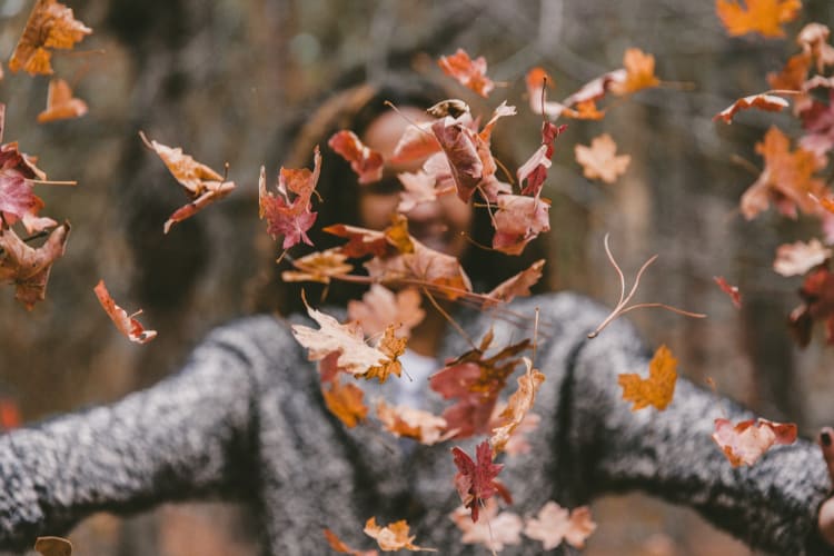 Woman playing with autumn leaves