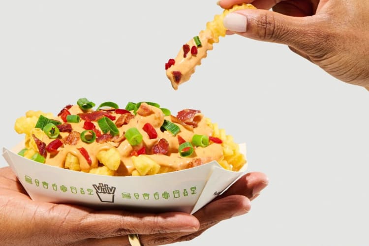 A hand grabbing a fry from a box of cherry pepper cheese fries
